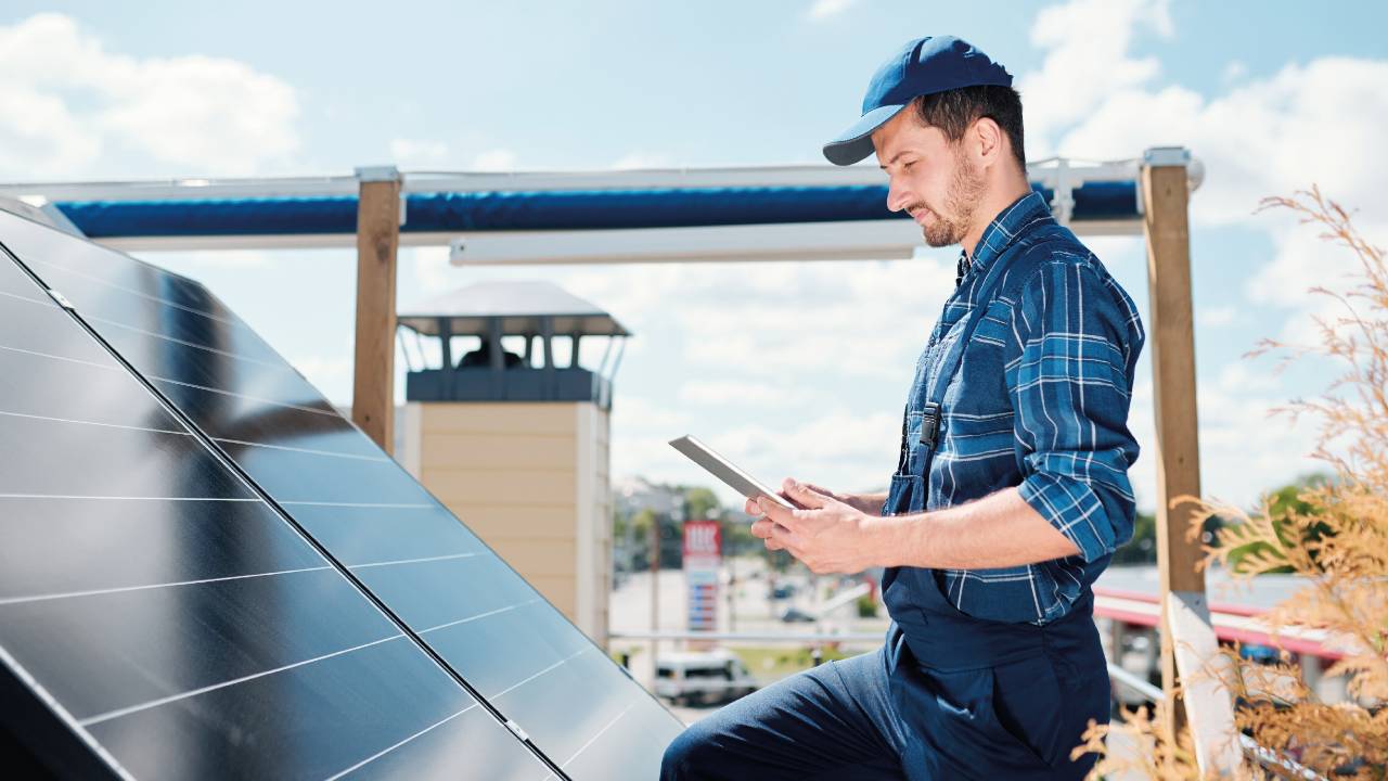 Hombre realizando mantenimiento preventivo a los paneles solares del techo de una casa