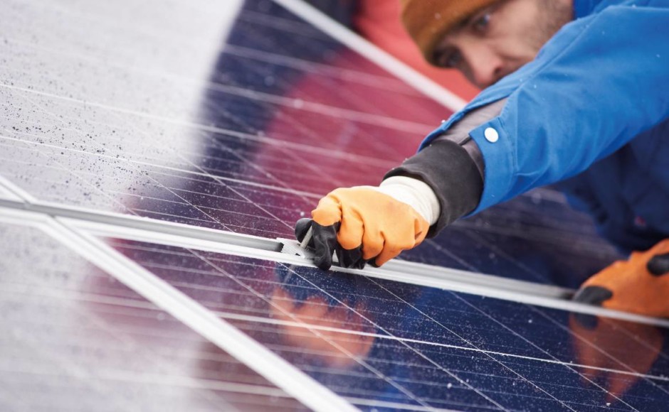 Hombre realizando limpieza y  mantenimiento preventivo a un panel solar