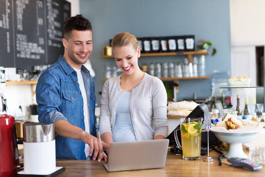 Hombre y mujer propietarios de un restaurante frente a un computador portátil