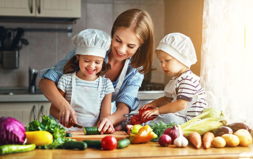 Madre preparando verduras con sus dos hijos pequeños
