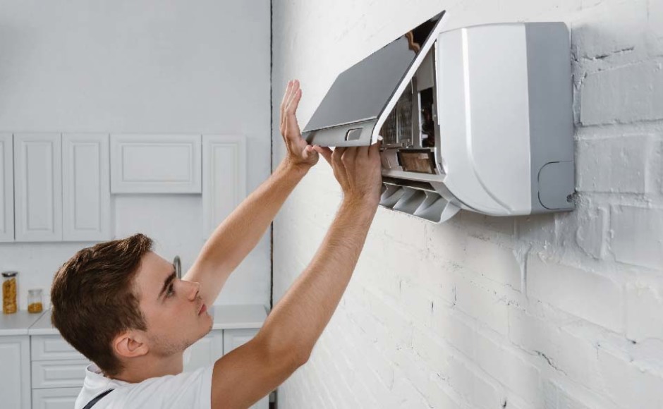 Hombre realizando mantenimiento preventivo a un aire acondicionado en la pared
