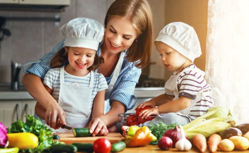 Mujer preparando cocina saludable con sus dos hijos en la cocina