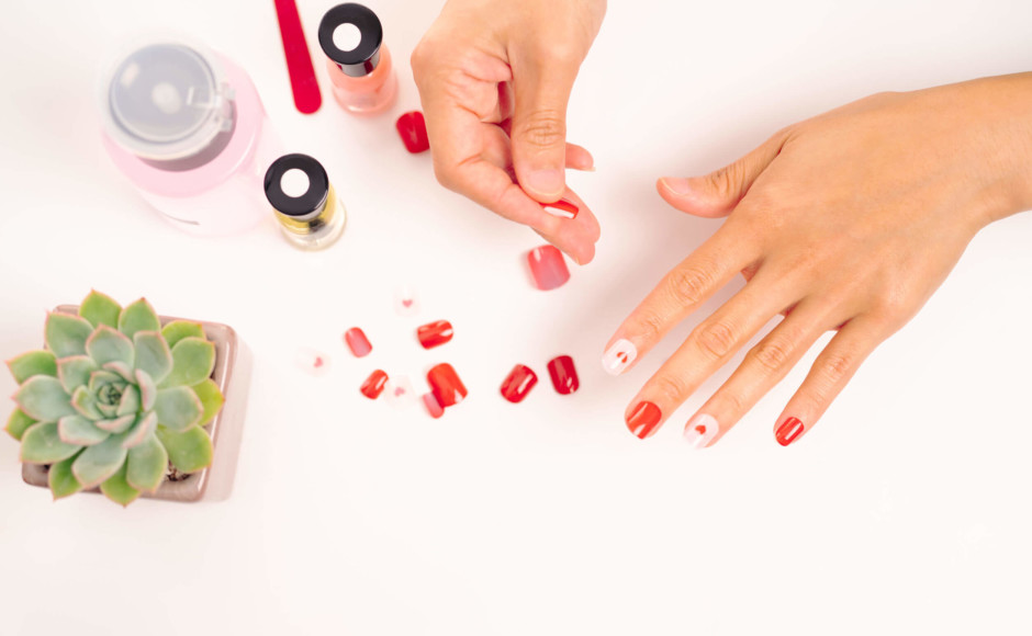 Manos de una mujer seleccionando diferentes tipos de uñas acrílicas