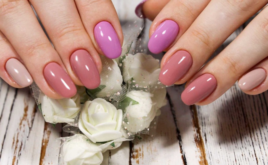 Dedos de las manos de una mujer con uñas acrílicas rosadas