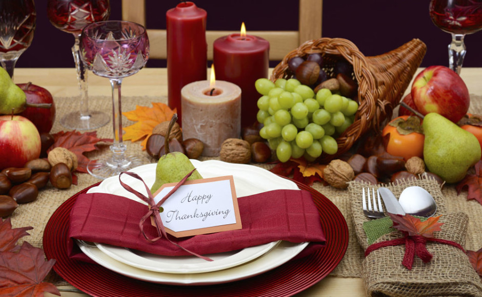 mesa de accion de gracias decorada con velas, frutas, cornucopia y una tarjeta