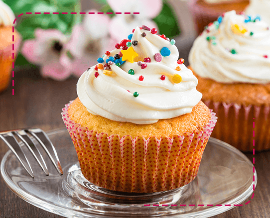 Cupcake con un decorado de crema y chispitas de colores sobre un plato.