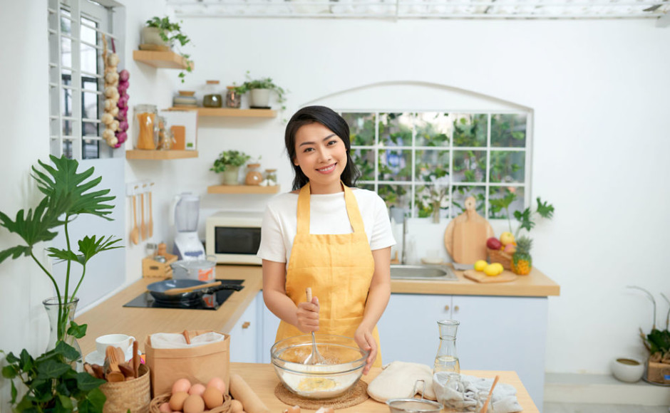 mujer batiendo huevos en un recipiente para hacer un pastel en su cocina