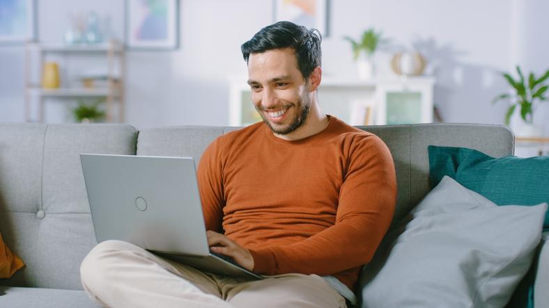hombre sonriendo mientras observa un computador