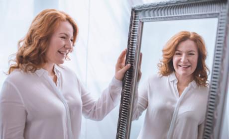 mujer mirandose y sonriendo frente a un espejo