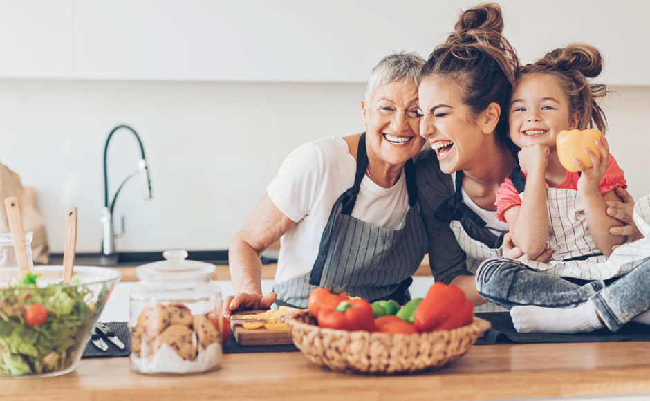 dos mujeres y una niña sonriendo rodeadas de alimentos saludables