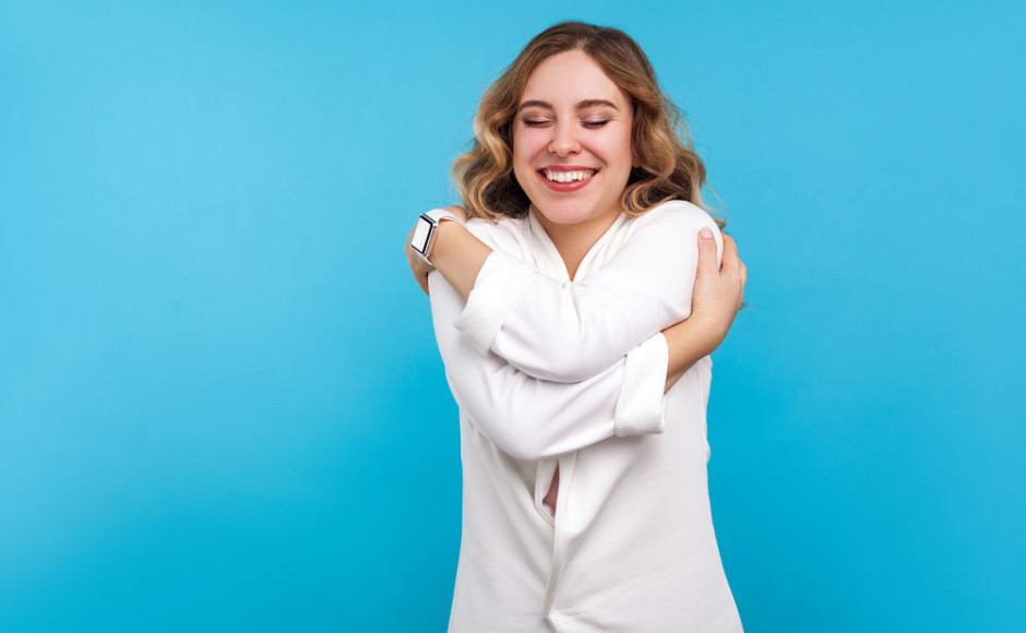 mujer abrazandose asi misma en un fondo azul