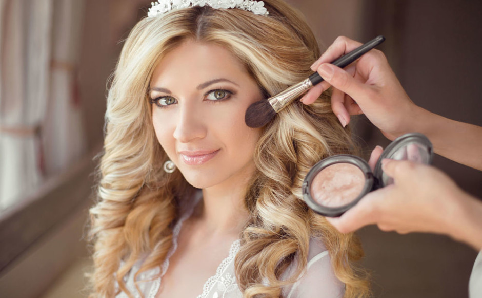 mujer vestida de novia siendo maquillaje