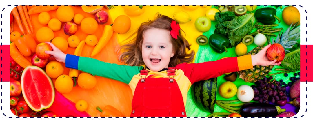 niña sonriendo sobre unas frutas y verduras
