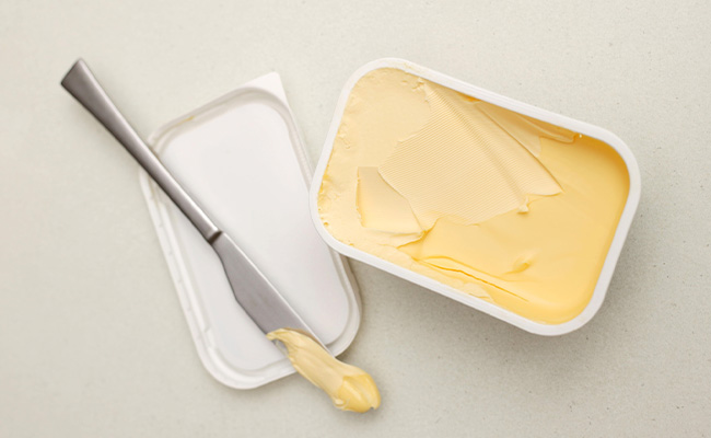 mantequilla en un recipiente junto a cuchillo untador
