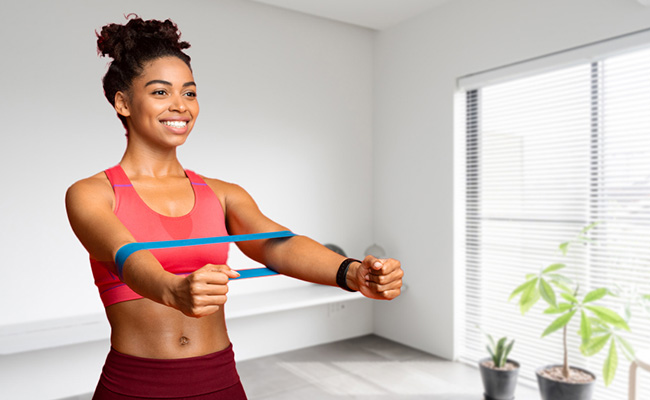 persona realizando un ejercicio de brazos con bandas elásticas en el living de su hogar