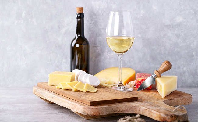 table de quesos junto a una botella y copa de vino
