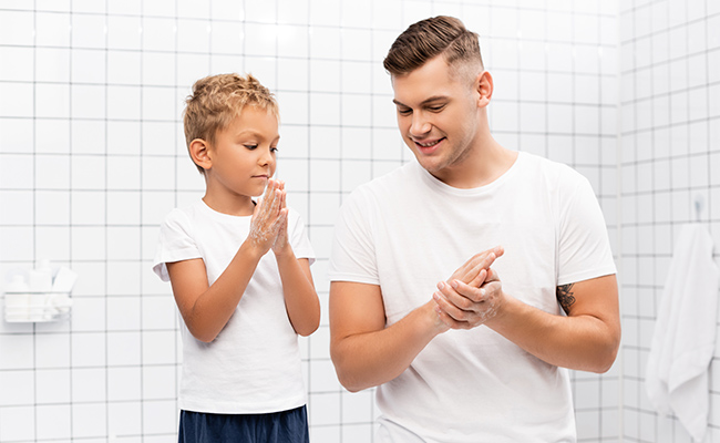 un papá enseñándole a su hijo a lavarse las manos