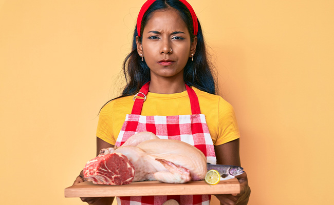 mujer pensativa sosteniendo una bandeja con diferentes tipos de carnes