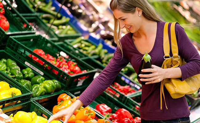 mujer en el mercado eligiendo verduras para comprar