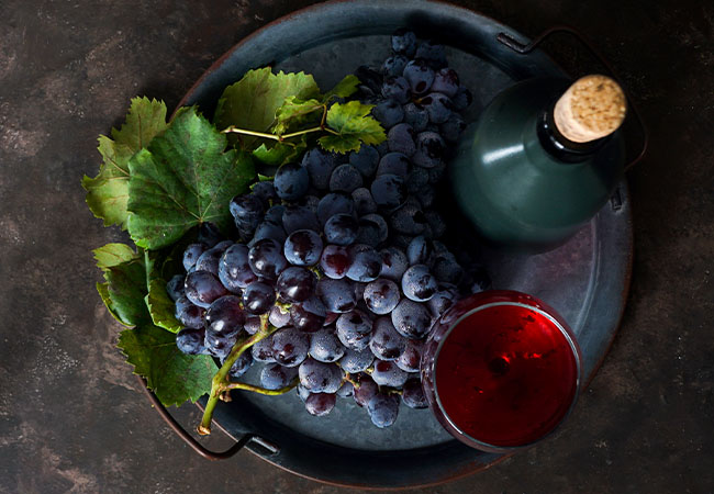 uvas merlot junto a una botella de vino