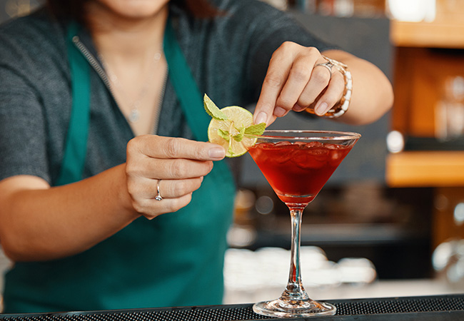 mujer bartender decorando un trago minimalista