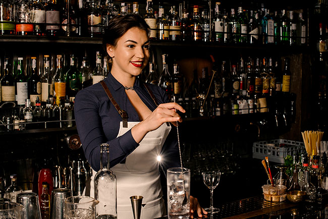 mujer bartender sirviendo un trago a un cliente