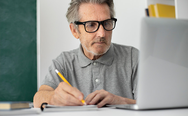 persona mayor estudiando frente a una computadora
