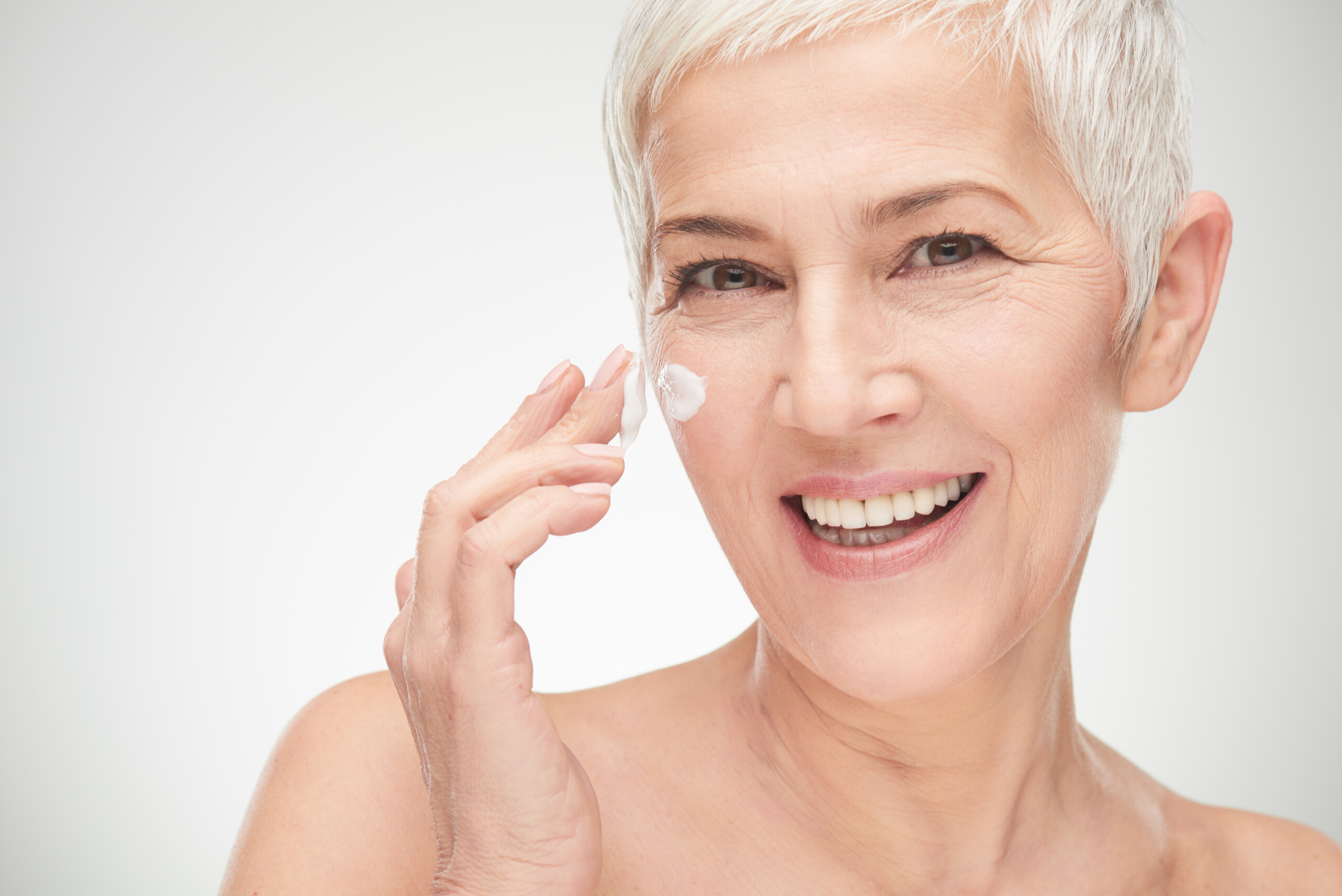 mujer de edad madura aplicando crema facial