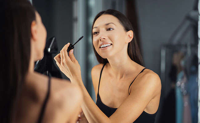 Mujer maquillándose enfrente de un espejo