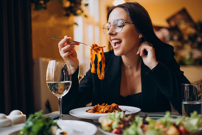 mujer probando un plato de pasta italiana