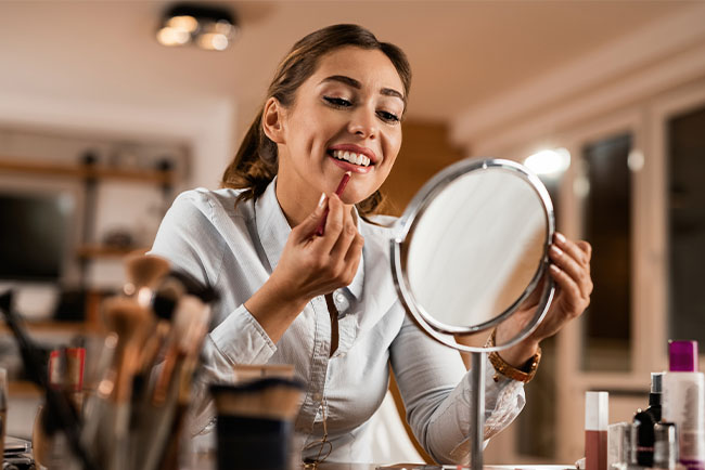 mujer colocandose labial frente al espejo