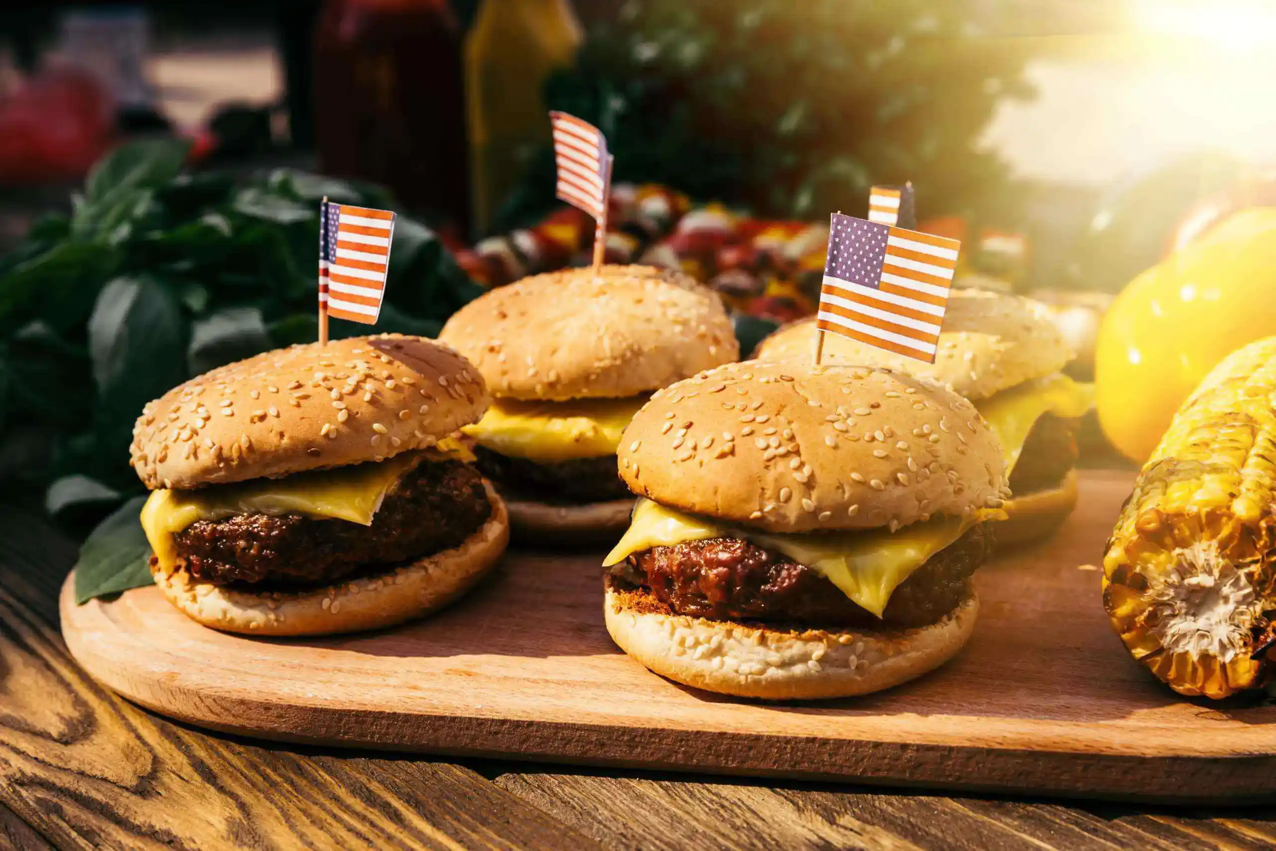 hamburguesas con banderin americano apoyadas sobre una tabla de madera