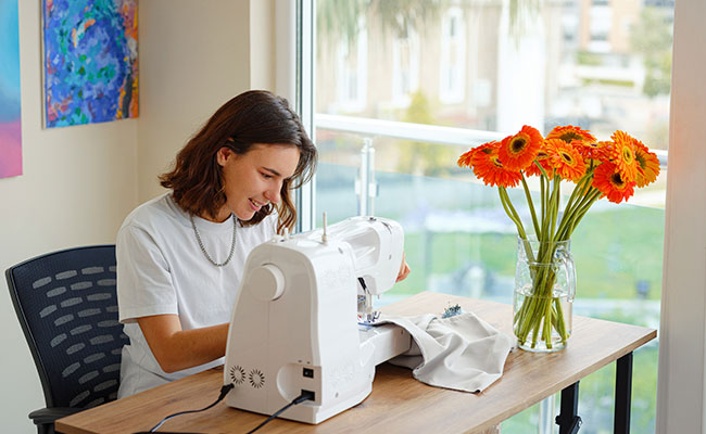 persona en su escritorio trabajando con su maquina de coser