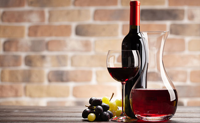 Una copa de vino, junto a un decantador y a una botella de vino