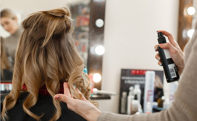 mujer aplicando productos al cabello de un cliente