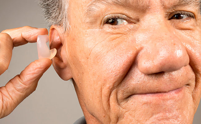 adulto mayor usando tapones de oídos