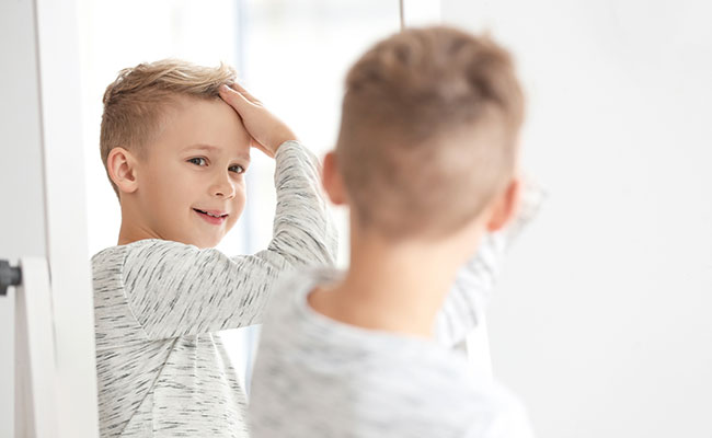 niño mirando su nuevo corte de pelo al espejo