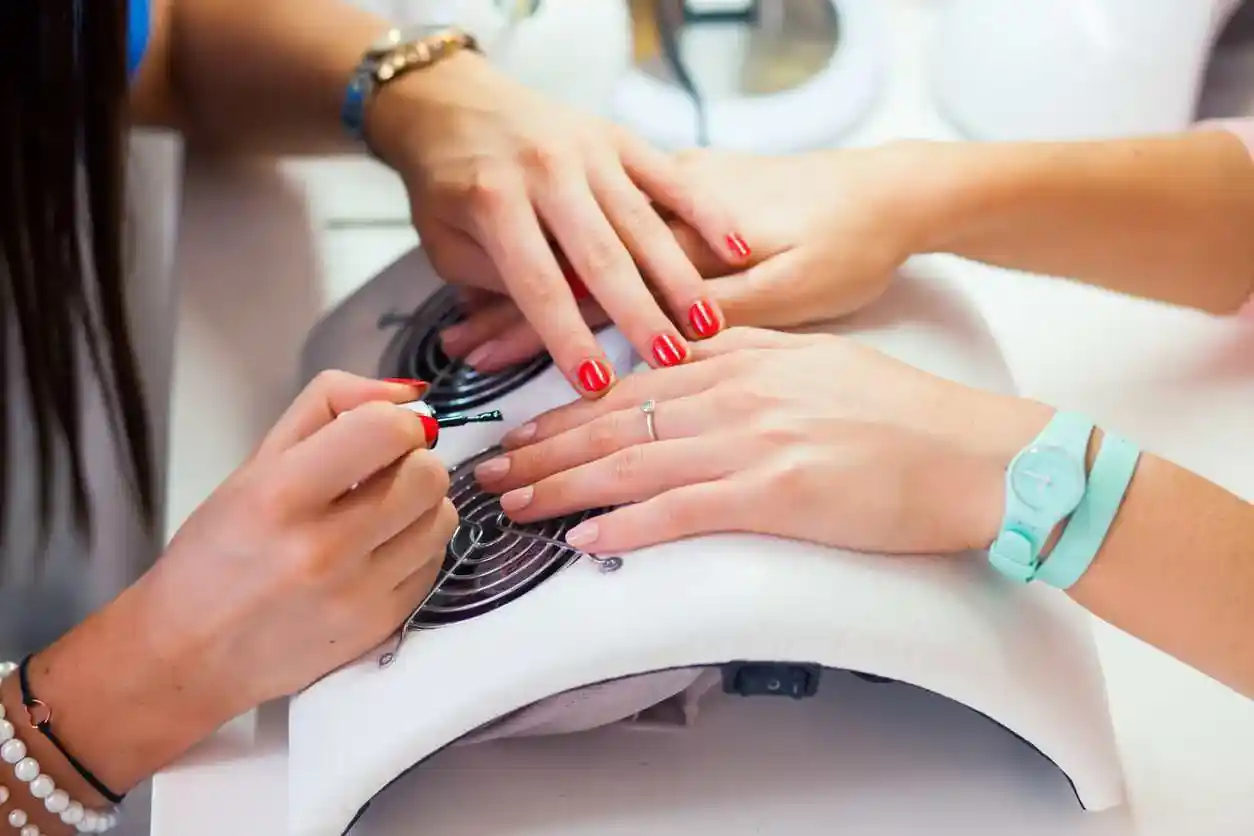 mujer esmaltando las uñas de su cliente