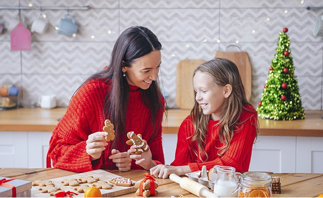 madre e hija decorando galletas de navidad en la cocina