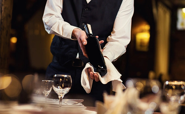 un mozo sirviendo una copa de vino a un cliente