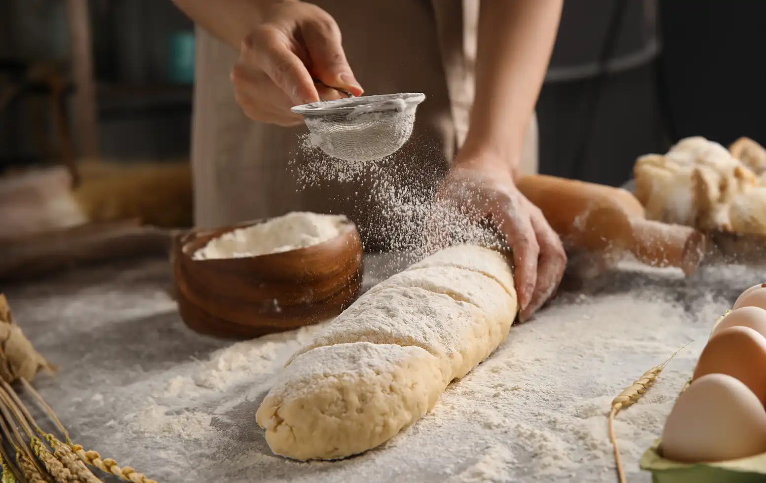 panadera espolvoreando harina sobre una baguette casera