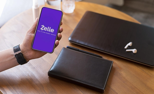 billetera sobre una mesa junto a un celular con la app de zelle abierta